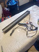 LED light bar placed on a white surface showing the entire length with wiring and mounting bracket.