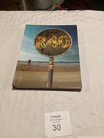 Cover of the Rush R40 tribute book showing a weathered street sign with 'R40' on a beach.