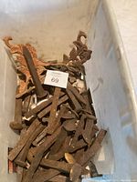 Top view of container filled with numerous old rusty railroad spikes showing varied sizes and patina.