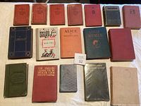 Full view of 16 vintage books laid out on table, showing various classic titles and different colored cloth bindings.