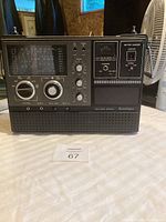 Front view of vintage radio showing tuning bands and multiple adjustment dials along with battery charger section.