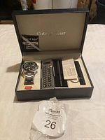Box containing Cote d'Azur watch, calculator, and warranty card with papers.