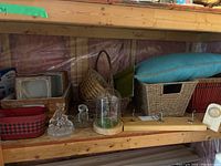 Wide view of shelf showing various baskets, small glass items, and a basket with blue cushion
