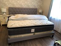 Full view of assembled grey upholstered king bed frame with mattress and box springs