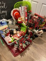 Wide shot showing multiple Christmas decorations including wrapping paper rolls, stockings, greenery, and various figurines grouped in bins and trays.