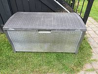 Outdoor resin wicker style deck box closed, showing front view and textured woven pattern.