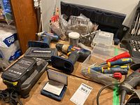 Overall view of two Ryobi cordless drills, battery, charger, screwdriver set, drill bits, and tool organizer on wooden table.
