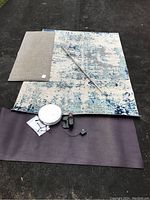 Photo showing all items: robot vacuum, charging base, blue and grey area rug, purple yoga mat, taupe vinyl cushioned runner, chrome shower rod placed across the mats.