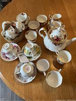 Full view of tea set components arranged on table including cups, saucers, cream, sugar, and teapot.