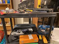 Full view of items on tool cart including hand tools, stud finders, Mastercraft power tool in case, Ryobi dustless sander, two stud finders and small tool set