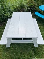 Top-down view of the small white wooden children's picnic table showing the surface and attached benches in outdoor garden setting.