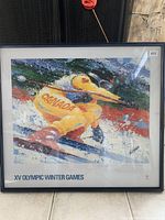 Framed poster showing a skier in a yellow Canada racing suit in a dynamic snow scene. Poster is signed "Wesman" and has frame in good condition.