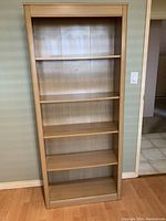 Front view of the wooden bookshelf showing all five shelves and light wood finish.