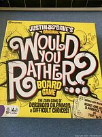 Close-up of Justin & Dave's Original Would You Rather board game box with prominent yellow color and distinctive typography.