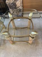 Smaller table showing clear glass top with beveled edges and brass frame with eagle heads at the corners.