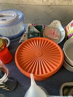 Close-up of salad spinner, orange plastic container, and surrounding kitchen items for detailed view.