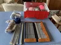 Two leather-trimmed roll-up cases each containing sets of metal knitting needles of varying sizes and length organized in order.