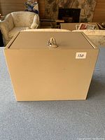 Front view of the beige metal safe with visible key in lock and sticker label on front.