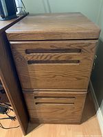 Front view of the two-drawer filing cabinet showing the oak finish and inset handles.
