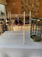 Two white metal shoe racks, one bamboo umbrella stand, and pairs of shoes arranged on top of the racks.