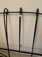 Close-up view of the wrought iron headboard showing vertical bars with decorative top loops and black finish.