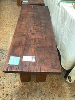 Top view of rustic solid wood bench showing long plank with visible grain and aged marks.