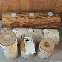Photo showing multiple birchwood candle holders in different sizes and styles, includes horizontal log holder and vertical cylindrical holders with tea light candles.
