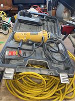 Dewalt DW660 cut-out tool resting on its black carrying case with a yellow extension cord coiled underneath