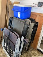 Blue Coleman cooler on top of stacked loungers and lawn chairs in corner