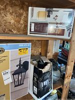 Shelved five lighting fixtures including boxed Hampton Bay lanterns and an Allen + Roth wall lamp box.