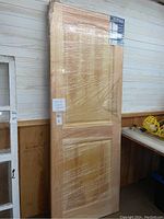 Two shrink-wrapped pine doors leaning against wall