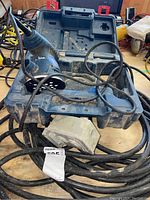 Bosch electric orbital sander resting in its molded black plastic carrying case with dusty condition.