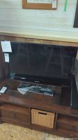 Full view of Samsung 32" flat screen TV on stand with wired remote in front, showing size and overall condition.
