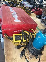 Hilti red carrying case with electrical cords and tools arranged on table surface