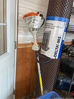 Full view of Stihl FS 40 C gas-powered pull start trimmer leaning against wall