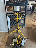 Cooper Lighting trouble light mounted on yellow tripod with three additional individual trouble lights and cords placed on floor beneath tripod.