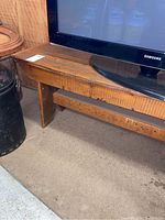 Side view of wooden bench showing thick plank seat and sturdy leg construction.