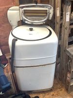 Overall view of vintage Kelvinator wringer washer showing top lid and wringer assembly, white enamel exterior with some wear and rust spots.