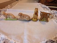 Photo showing all four Wade Woppas animal figurines: Otter, Chipmunk, Stoat, and Bobcat, arranged in a row on a white lace-trimmed cloth.