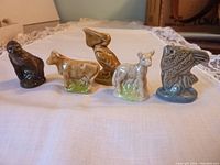Five Wade ceramic animal figures displayed in a row on a white lace cloth with a neutral background.