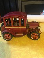 Side view of red vintage Japanese tin battery-operated toy car with window detailing and classic design.