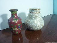Both cloisonne pieces displayed side by side on a wooden surface with a light blue and white background.