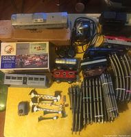 Overview of Marx O scale train set parts including locomotives, cars, tracks, building kit and accessories on table