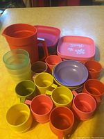 Array of colorful toy Tupperware including cups, plates, bowls, pitcher and containers.