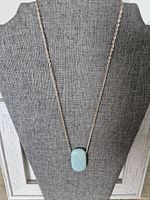 Full view of silver chain necklace with amazonite stone pendant displayed on gray fabric bust.