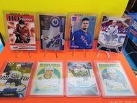 Photo showing 8 NHL rookie cards in protective sleeves, arranged in two rows against a yellow background.