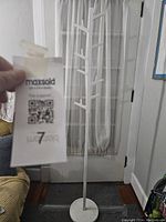 White coat tree with a hand holding the lot ticket for inventory.