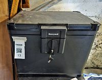 Front view of black Honeywell safe with key inserted in lock, showing locking mechanism and top lid seam.