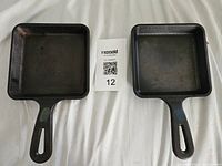 Top-down view of two mini cast iron square skillets side-by-side on white background showing overall condition and size.