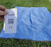Blue moving blanket laid on grass, showing quilted chevron textured pattern, clean condition